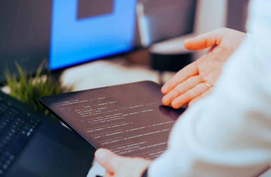 Softverski developer analizira kod na tabletu u modernom uredu